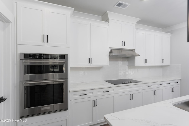 778 Hollybriar Loop Rd SE, Bolivia, NC 28422 - kitchen with double oven, black electric stovetop, under cabinet range hood, white cabinetry, and tasteful backsplash