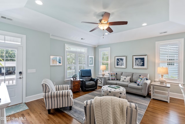 living room featuring baseboards, a raised ceiling, wood finished floors, and recessed lighting