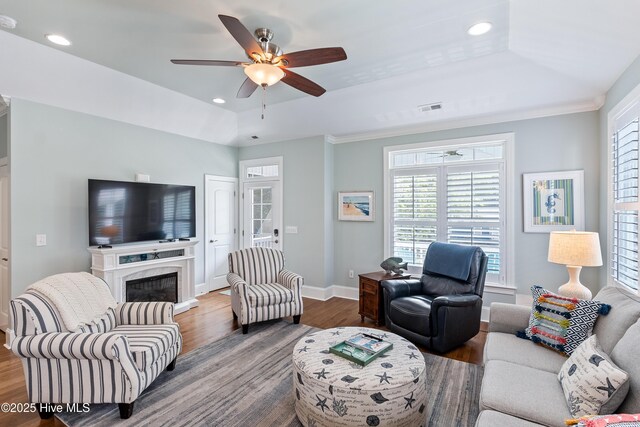 living room with wood finished floors, baseboards, a raised ceiling, ceiling fan, and recessed lighting