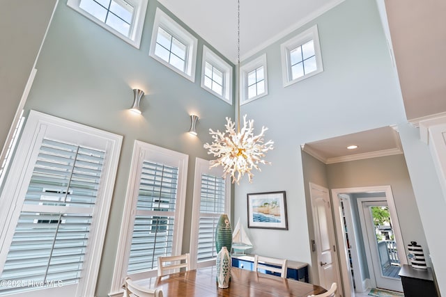 dining area featuring a high ceiling, ornamental molding, and healthy amount of natural light