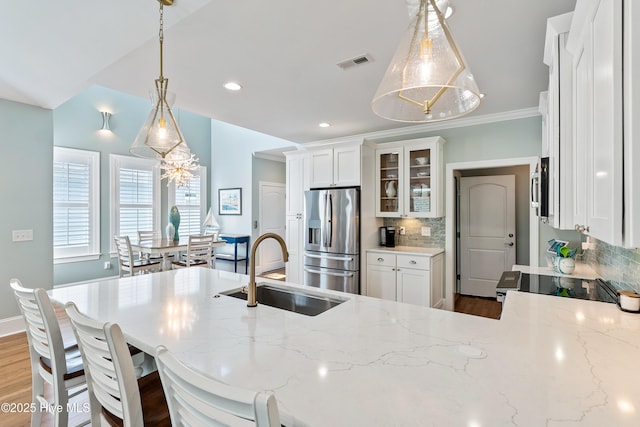 kitchen featuring stainless steel appliances, a sink, backsplash, light stone counters, and recessed lighting