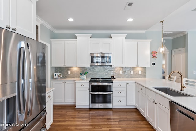 kitchen with stainless steel appliances, a sink, ornamental molding, light countertops, and white cabinetry