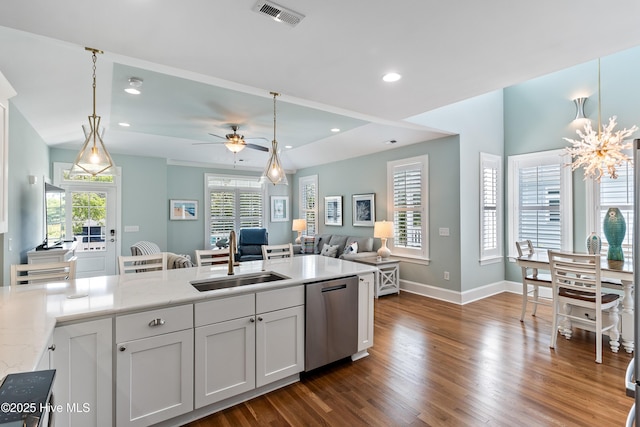 kitchen with stainless steel dishwasher, a sink, dark wood-style flooring, open floor plan, and hanging light fixtures