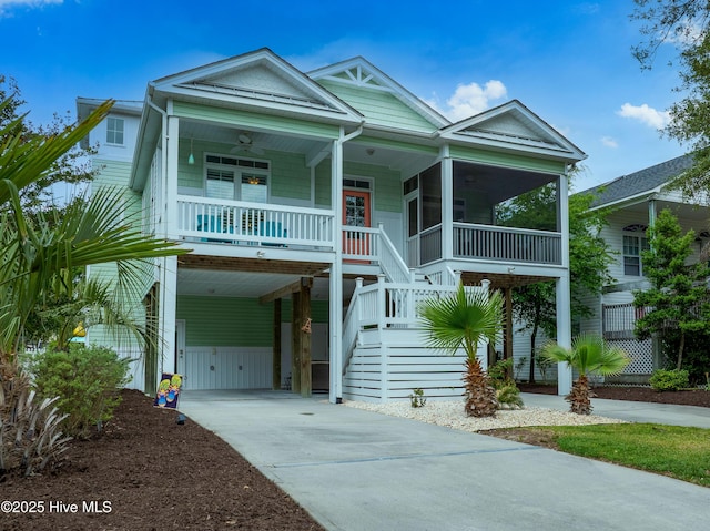 coastal inspired home featuring a ceiling fan, driveway, a carport, a porch, and stairs