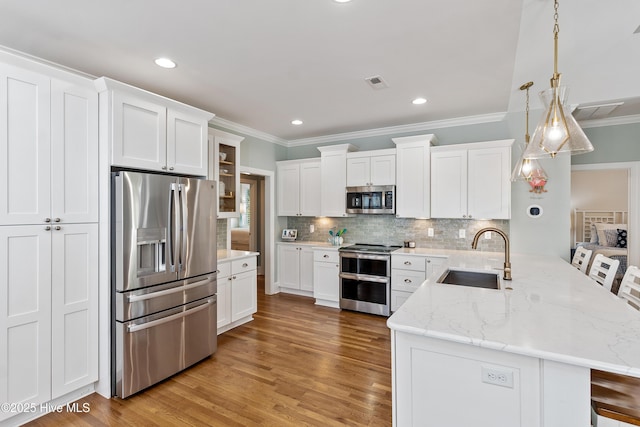kitchen featuring appliances with stainless steel finishes, a sink, a peninsula, white cabinets, and ornamental molding