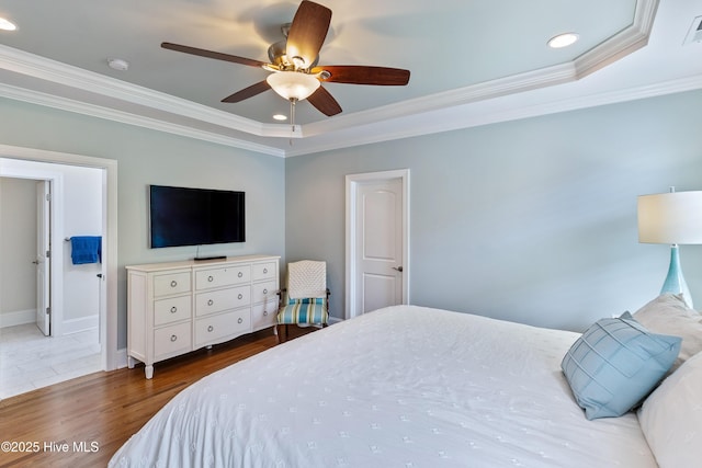 bedroom featuring crown molding, recessed lighting, wood finished floors, a tray ceiling, and baseboards