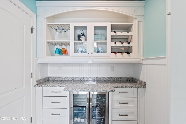 bar area featuring beverage cooler and a wainscoted wall
