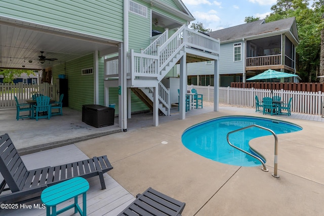 view of swimming pool featuring a ceiling fan, a sunroom, a fenced backyard, and outdoor dining space