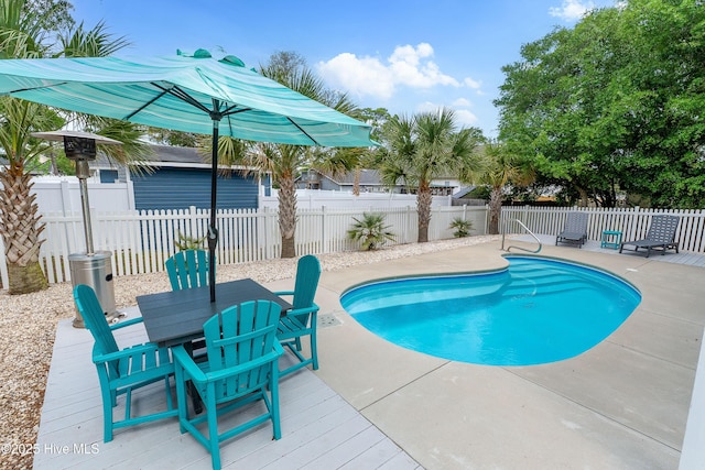 view of swimming pool featuring fence, outdoor dining area, a wooden deck, and a patio
