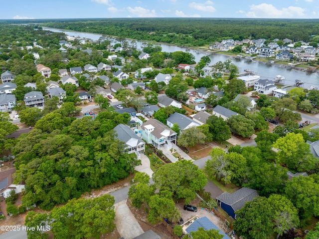 aerial view of residential area featuring a nearby body of water and a forest