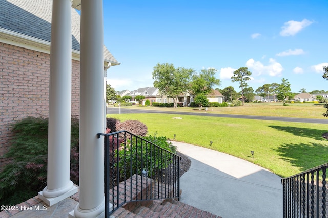view of grassy yard with a residential view and a porch