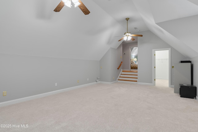 additional living space with a ceiling fan, light colored carpet, vaulted ceiling, stairway, and baseboards