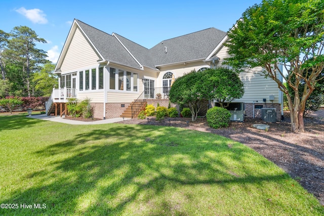 rear view of property with stairway, a sunroom, a yard, and a shingled roof