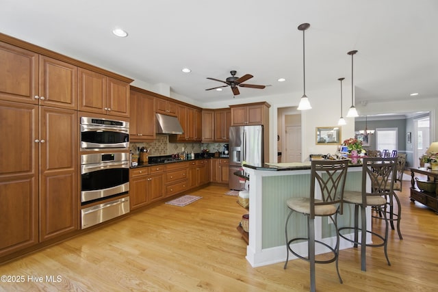 127 Meherrin River Dr, Hertford, NC 27944 - kitchen with a warming drawer, appliances with stainless steel finishes, under cabinet range hood, a breakfast bar area, and brown cabinetry