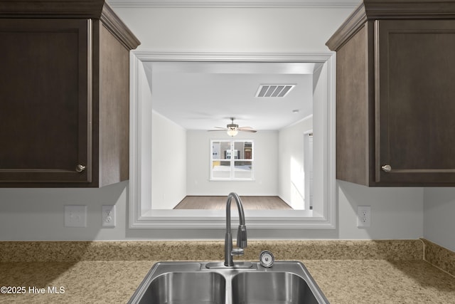 kitchen featuring a sink, dark brown cabinets, light countertops, and ceiling fan