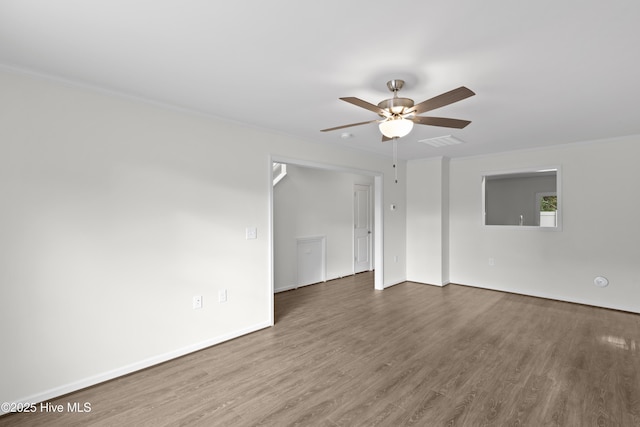 spare room featuring crown molding, wood finished floors, ceiling fan, and baseboards
