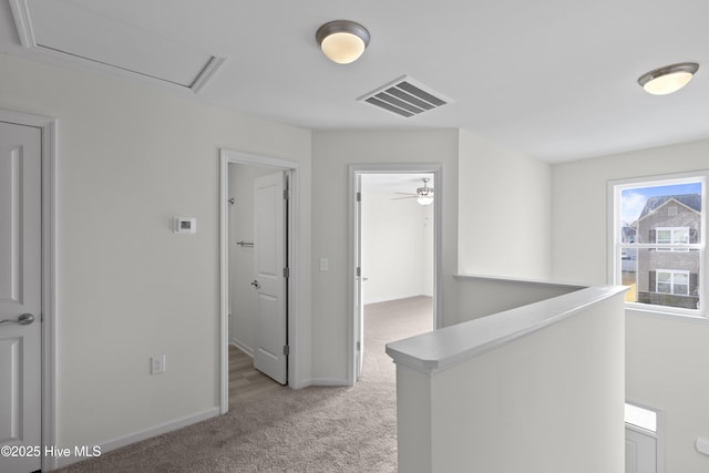corridor featuring light colored carpet, an upstairs landing, and baseboards