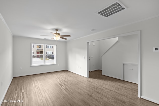 unfurnished room featuring ornamental molding, wood finished floors, a ceiling fan, and baseboards