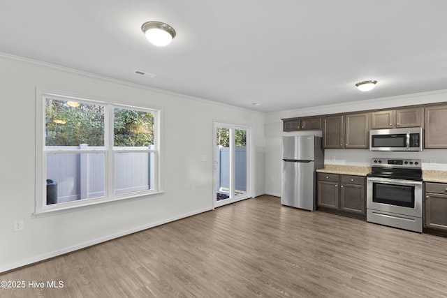 kitchen with stainless steel appliances, light wood-style flooring, ornamental molding, baseboards, and dark brown cabinets
