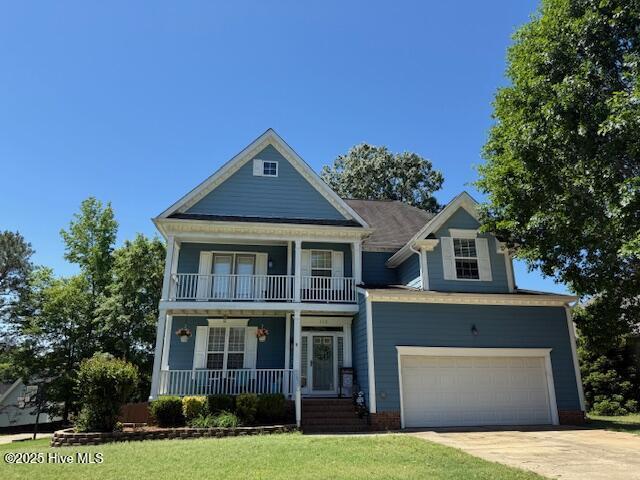 view of front of house with a porch, a balcony, concrete driveway, and a front yard