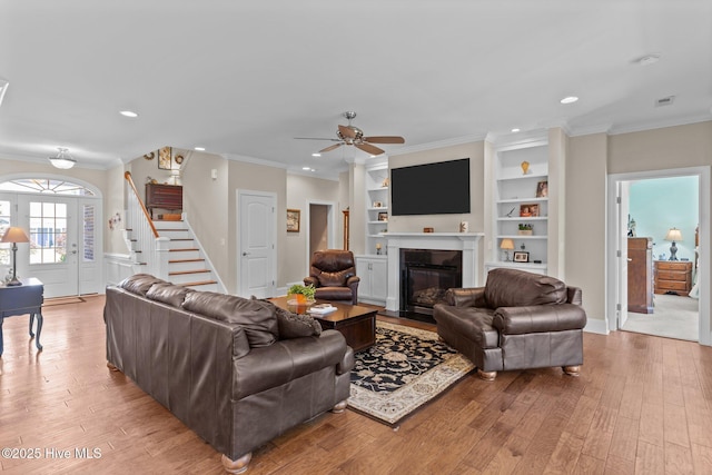 living area featuring recessed lighting, light wood finished floors, stairs, ceiling fan, and a glass covered fireplace
