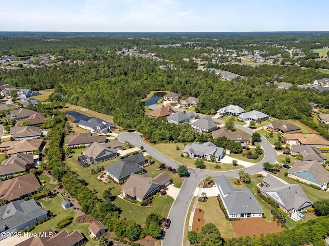 aerial view of property and surrounding area with nearby suburban area, a large body of water, and a heavily wooded area
