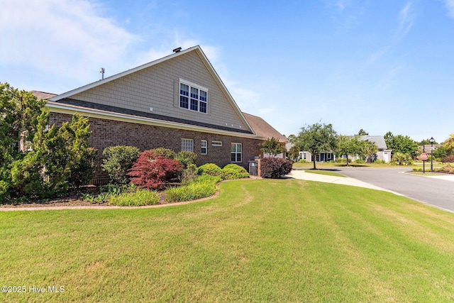 view of side of home with a lawn and brick siding