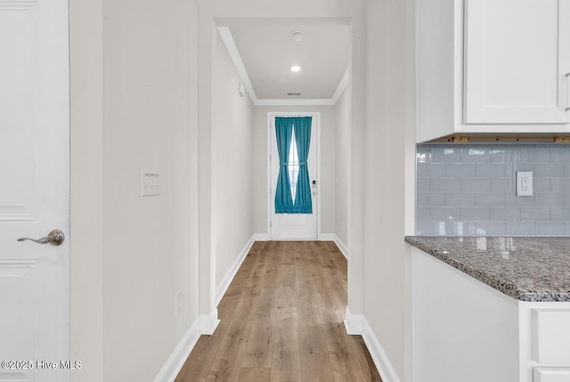 corridor featuring light wood-style floors, ornamental molding, and baseboards