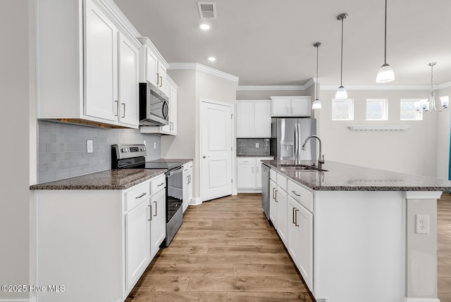kitchen featuring appliances with stainless steel finishes, a sink, ornamental molding, light wood-style flooring, and white cabinetry