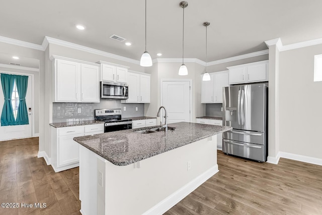 kitchen featuring stainless steel appliances, a sink, light wood-type flooring, white cabinets, and dark stone counters