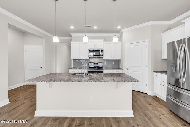 kitchen featuring stainless steel appliances, a sink, dark stone countertops, tasteful backsplash, and ornamental molding