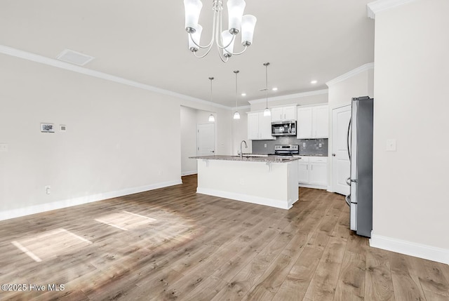 kitchen featuring appliances with stainless steel finishes, a sink, crown molding, decorative backsplash, and a chandelier