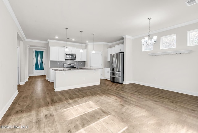 kitchen featuring stainless steel appliances, a chandelier, wood finished floors, white cabinetry, and a kitchen island with sink