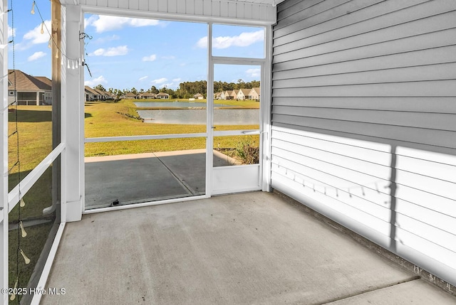 unfurnished sunroom featuring a water view and a residential view