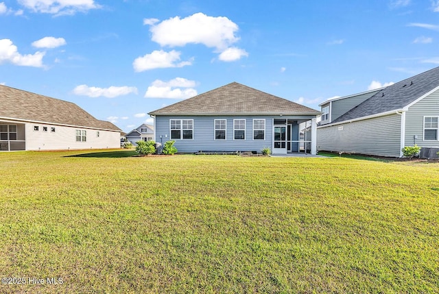 rear view of property featuring a lawn, a sunroom, and central AC