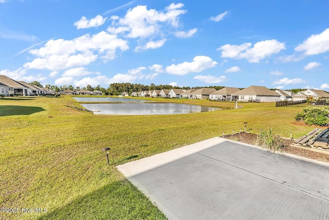 view of green lawn with a residential view, a water view, and a patio area