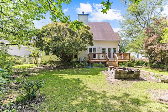 rear view of house featuring a fire pit, a deck, a chimney, and roof with shingles