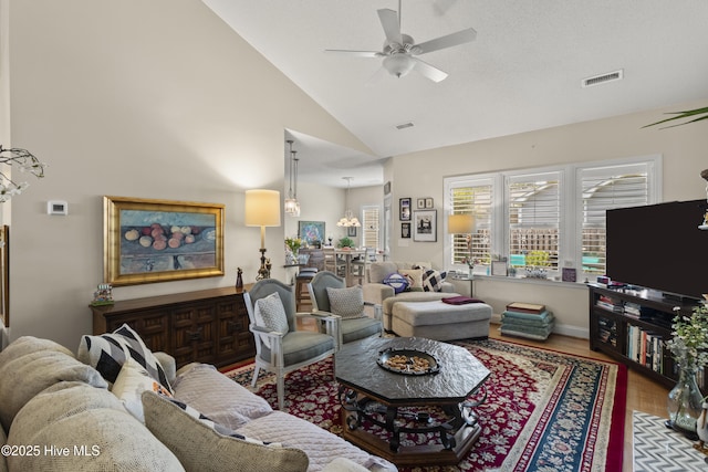 living area with a ceiling fan, wood finished floors, baseboards, and high vaulted ceiling