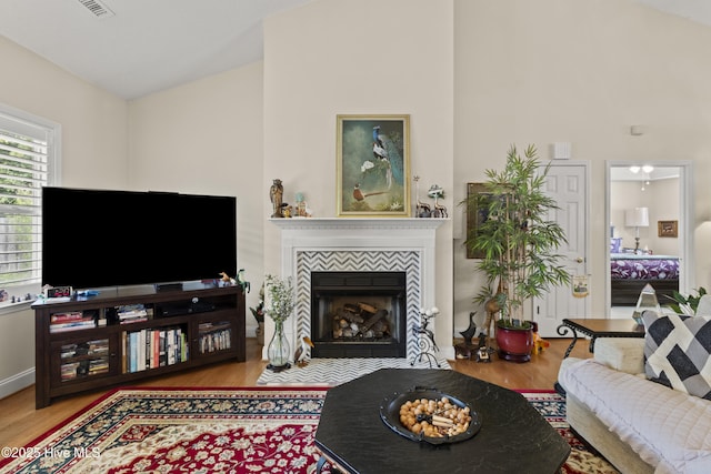 living area with wood finished floors, a tiled fireplace, and baseboards