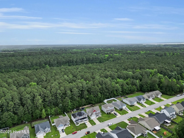 view of property location with a heavily wooded area and nearby suburban area