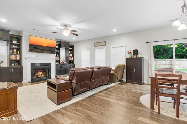 living room with a fireplace with flush hearth, wood finished floors, a ceiling fan, and recessed lighting