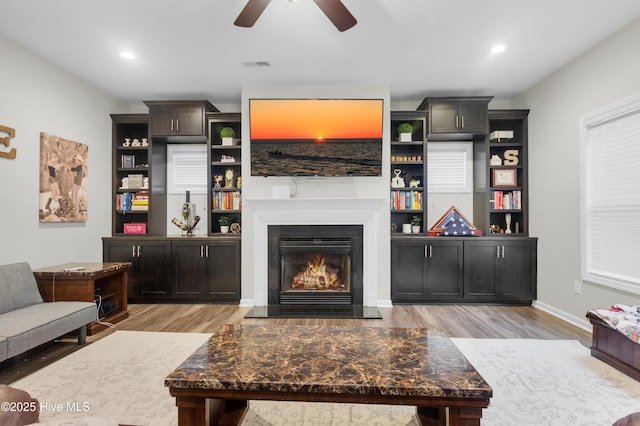 living room with light wood finished floors, ceiling fan, a glass covered fireplace, baseboards, and recessed lighting
