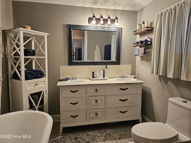bathroom featuring toilet, a soaking tub, backsplash, and double vanity