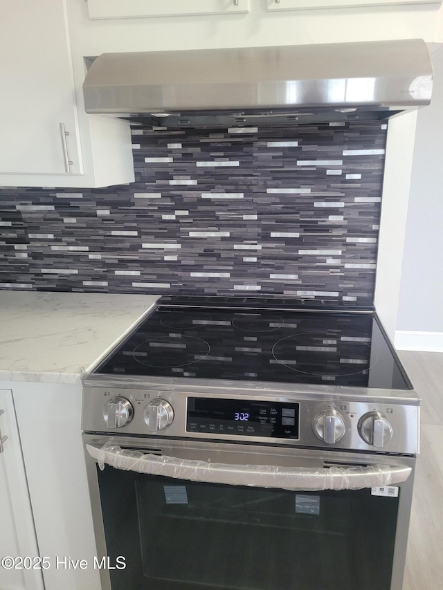 4384 Race Track Rd, Grifton, NC 28530 - kitchen view of decorative backsplash, stainless steel electric range, white cabinetry, light stone counters, and exhaust hood