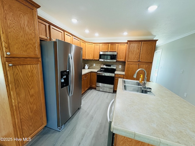 106 Haywood Country Dr, Mount Gilead, NC 27306 - kitchen featuring stainless steel appliances, a sink, light wood finished floors, brown cabinetry, and crown molding