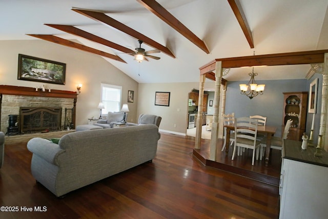 living room with ceiling fan, a stone fireplace, a chandelier, dark wood finished floors, and baseboards