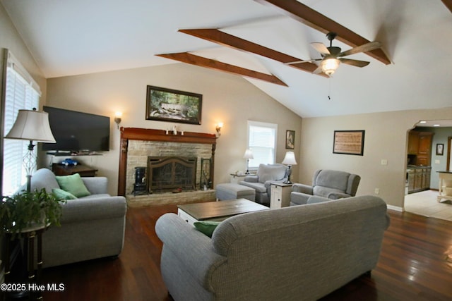 living room featuring a ceiling fan, a stone fireplace, arched walkways, wood finished floors, and baseboards