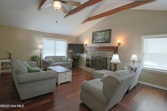 living room with ceiling fan, beamed ceiling, a stone fireplace, plenty of natural light, and high vaulted ceiling