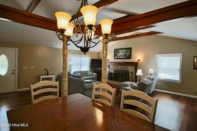 dining room featuring a chandelier, a stone fireplace, baseboards, and dark wood finished floors