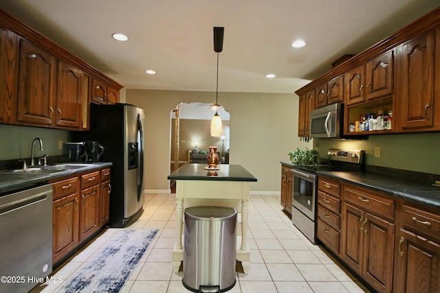 kitchen with stainless steel appliances, dark countertops, a sink, recessed lighting, and decorative light fixtures